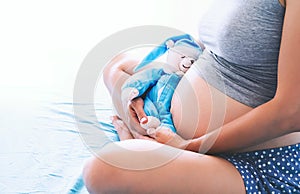 Close-up pregnant woman`s belly with teddy toy bear.