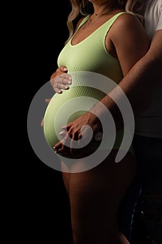 Close-up of a pregnant woman& x27;s stomach, her husband& x27;s hands on her stomach.