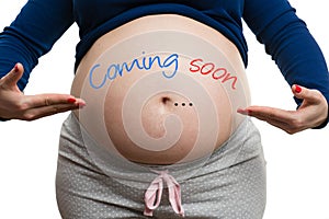 Close-up of pregnant woman showing her belly with coming soon text on it