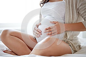 Close up of pregnant woman sitting in bed at home