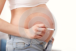 Close up of pregnant woman smoking cigarette at home