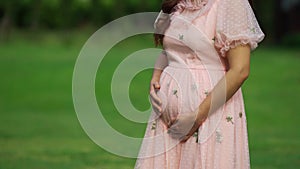 Close up pregnant woman stroking her belly in garden