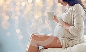 Close up of pregnant woman with tea cup in bed