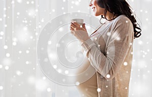 Close up of pregnant woman with tea cup at window