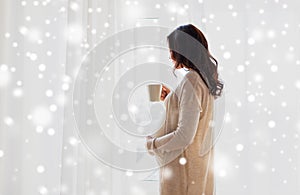 Close up of pregnant woman with tea cup at window