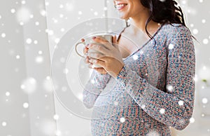 Close up of pregnant woman with tea cup at window