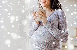 Close up of pregnant woman with tea cup at window