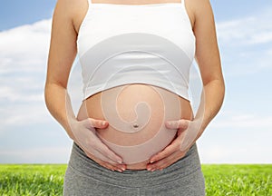 Close up of pregnant woman touching her bare tummy