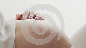 Close-up of pregnant woman touching her belly. Pregnancy, motherhood, and expectation concept