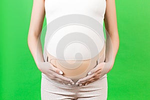 Close up of pregnant woman wearing pregnancy corset against backpain at green background with copy space. Orthopedic abdominal