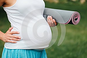 Close-up pregnant yoga woman with mat portrait in park on the grass, breathing, stretching, statics. outdoor, forest.