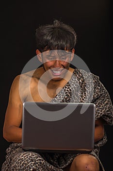 Close up of prehistoric man working in his computer, in a black background