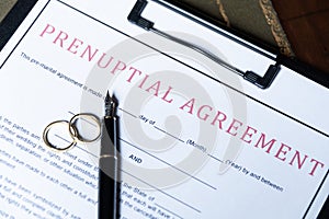 Close-up of a prenuptial agreement form with wedding rings and a fountain pen, indicating the legal aspects of marriage