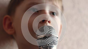 Close-up preschooler caucasian portrait with microphone sings a song. The child sings karaoke. Happy kid sings a song. Young vocal