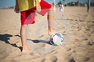 Close-up of preteen boy playing football on beach