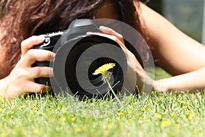 Close up of a pretty girl taking a photograph of a flower on the grass