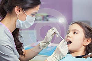 Close-up of pretty little girl opening his mouth wide during treating her teeth by the dentist