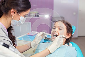 Close-up of pretty little girl opening his mouth wide during treating her teeth by the dentist