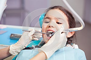 Close-up of pretty little girl opening his mouth wide during treating her teeth by the dentist