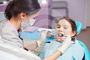 Close-up of pretty little girl opening his mouth wide during treating her teeth by the dentist