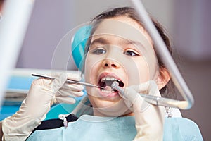 Close-up of pretty little girl opening his mouth wide during treating her teeth by the dentist