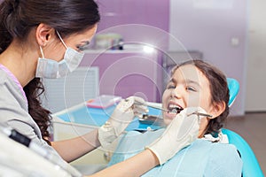 Close-up of pretty little girl opening his mouth wide during treating her teeth by the dentist