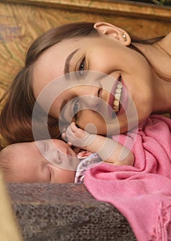 Close-up pretty woman kisses a newborn baby in her arms