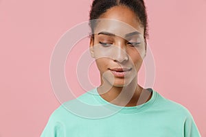 Close up of pretty young african american woman girl in green sweatshirt posing isolated on pastel pink wall background