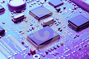 Close up of printed circuit board with electronic components toned blue and purple selective focus