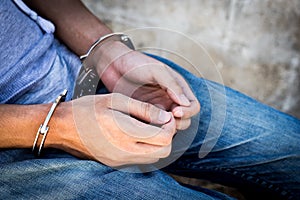 Close up prisoner hands in handcuffs. Arrested man in handcuffed hands