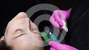 Close-up of the procedure of permanent makeup of the eyebrows, the master makes a tattoo
