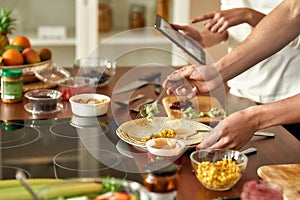 Close up of process of cooking. Man preparing meal while woman checking recipe using tablet. Vegetarians cooking in the