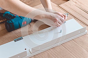 Close-up of the process of installation a furniture with electric screwdriver