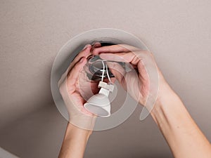 Close-up of the process of repairing and replacing an LED lamp on the ceiling. A man repairs a soffit