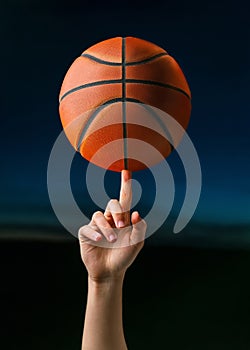 Close up of professional basketball player spinning a ball on hand finger. Street basketball athlete training for competition