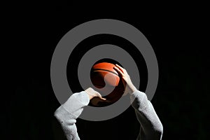 Close up of professional basketball player throwing a ball at night. Street basketball athlete training for competition in the