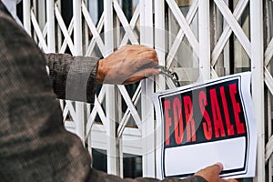 Close up of professional business man putting for sale box panel on the closed door of a store  concept of selling and buying