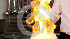 Close-up of a professional chef in black gloves in the kitchen of a restaurant cooks in the style of Flambe.Fruits and