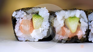 Close-up of professional chef`s hands in transparent gloves making sushi and rolls in a restaurant kitchen. Japanese traditional f