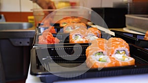 Close-up of professional chef`s hands in transparent gloves making sushi and rolls in a restaurant kitchen. Japanese traditional f