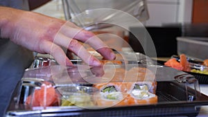 Close-up of professional chef`s hands in transparent gloves making sushi and rolls in a restaurant kitchen. Japanese traditional f