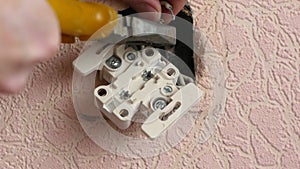 Close-up of a professional electrician prepares the electrical wires for replacing the socket. Home electrical appliance repair. E