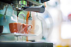 Close up professional espresso machine make coffee pouring into cup.
