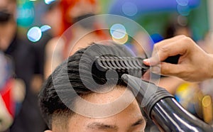 Close-up professional hairdresser using hair dryer and comb and accessories for beautiful and decorating men hair Cutting hair for