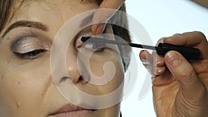 Close-up of professional make-up artist dyes the eyes of the model with a large brush. fashion industry cosmetics
