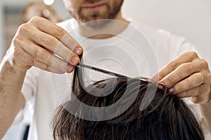 close-up, professional male hairstylist combing young customer& x27;s hair