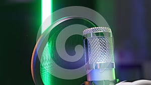 Close-up professional microphone for dubbing and singing in recording studio in rays of colorful floodlights. Studio