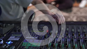 Close-up. Professional mixing console in the studio, a man's hand controls the sound, with LED backlight