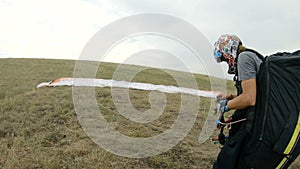 Close-up professional paraglider pilot prepares for takeoff, buttoning equipment and straightening slings