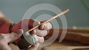 Close-up of a professional potter`s hands sculpting a clay bowl mold using a special wooden tool. A potter makes a clay product